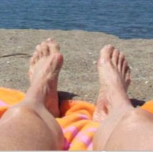 Photo of feet on beach blanket, ocean in front